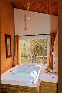 eine große Badewanne in einem Zimmer mit Fenster in der Unterkunft Middle House in Campos do Jordão