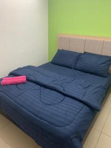 a bed with a blue comforter and a pink pillow at Risqi Apartment 2 bedroom Wakaf Che Yeh in Kota Bharu