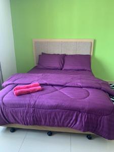 a purple bed with two pink pillows on it at Risqi Apartment 2 bedroom Wakaf Che Yeh in Kota Bharu
