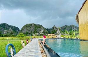 a woman standing on a dock next to a swimming pool at Hang Mua Bungalow in Ninh Binh