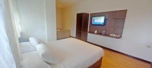 雅加达Hotel Aruni Ancol的一间卧室配有一张床,墙上配有电视