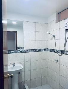 a white tiled bathroom with a sink and a shower at Hotel Puerto Bayovar II in Mala