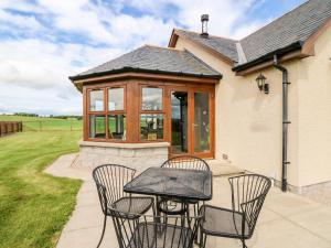 a patio with four chairs and a table at Kilnary Cottage in Ellon
