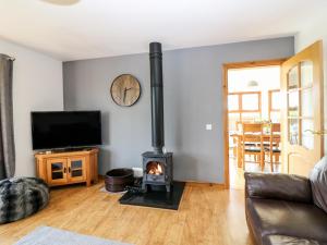 a living room with a fireplace and a tv at Kilnary Cottage in Ellon