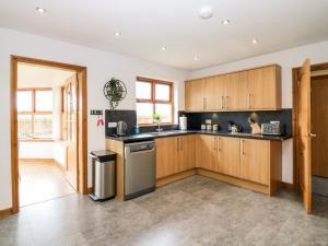 a kitchen with wooden cabinets and a sink and a dishwasher at Kilnary Cottage in Ellon