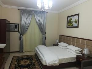 ein Schlafzimmer mit einem weißen Bett und einem Kronleuchter in der Unterkunft نسيم الفجر للشقق المخدومة in Dschidda