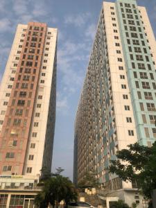 two tall buildings with palm trees in front of them at Apartment Grand Sentraland Karawang Manage by Laguna Room in Karawang