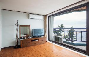 a living room with a television and a large window at Benikea Hotel Mountain & Ocean Sokcho in Sokcho