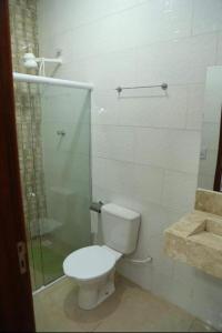 a bathroom with a toilet and a glass shower at Canions Pousada in Canindé de São Francisco