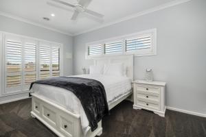 a white bedroom with a bed and two windows at The Oxley Estate in Portarlington