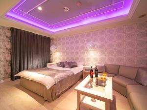 a bedroom with a bed and a couch and purple lighting at Hotel Rocco (Adult Only) in Nara