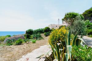 un jardin avec un phare sur une colline à côté de l'océan dans l'établissement Villa Tina ai Piedi del Faro di Leuca, à Leuca