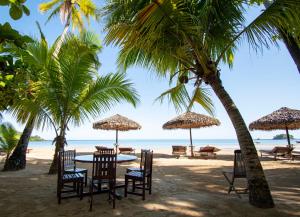 un tavolo e sedie su una spiaggia con palme di Andilana Lodge ad Andilana