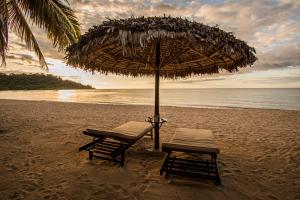 due sedie e un ombrellone su una spiaggia di Andilana Lodge ad Andilana
