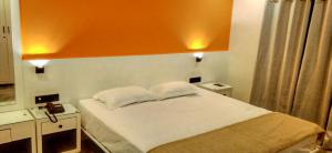 a bedroom with a bed with an orange wall at Providence, Port Blair in Port Blair