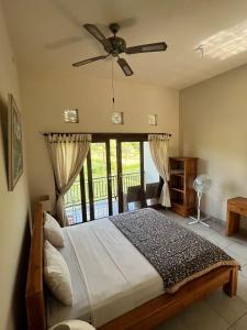 a bedroom with a bed with a ceiling fan at Mesari Homestay & Warung in Amed