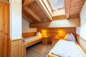 an attic room with two beds and a window at Hof am Schloss Apartement Zirm in Montechiaro