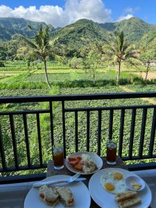 a table with two plates of food on a balcony at Mesari Homestay & Warung in Amed