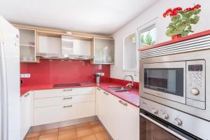 a kitchen with red walls and white cabinets at Cas Pobres in Sóller