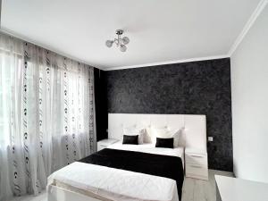 1 dormitorio con cama blanca y pared negra en TEA Apartments, en Pomorie