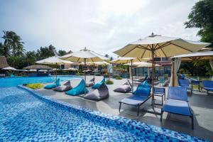 una piscina con sillas y sombrillas azules en Holiday Villa Beach Resort Cherating, en Cherating