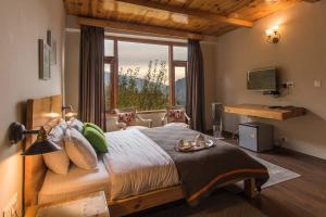 una camera da letto con un grande letto con una grande finestra di StayVista at Tulip Terraces a Manāli