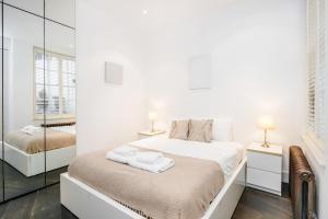a white bedroom with two beds and a mirror at Beautiful 2 bedroom Covent Garden apartment in London