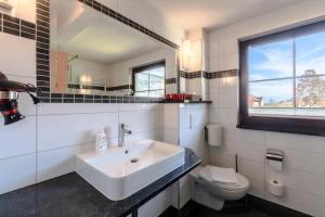 a white bathroom with a sink and a toilet at schöne Ferienwohnungen am Lobber Deich in Lobbe