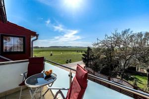 uma varanda com uma mesa e cadeiras e vista para um campo em schöne Ferienwohnungen am Lobber Deich em Lobbe