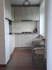 una cocina con armarios blancos, mesa y taburetes en Trumpalaikė nuoma centre en Šiauliai