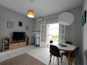a living room with a table and chairs and a television at Asprokavos beach apartment and studio in Kavos