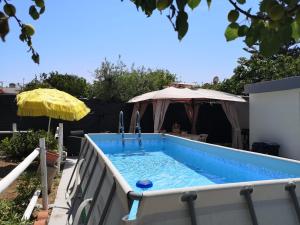 a swimming pool in a backyard with an umbrella at villa mina con vasca idromassaggio in Taranto