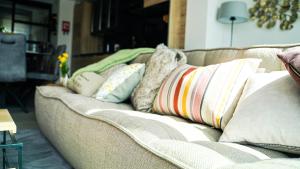 un sofá con almohadas en la sala de estar en Le Paradis d'Henri, en Hannut