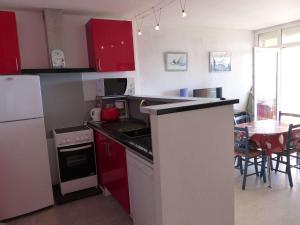 une cuisine avec des placards rouges et une table avec des chaises dans l'établissement Appartement Le Lavandou, 2 pièces, 4 personnes - FR-1-308-61, au Lavandou