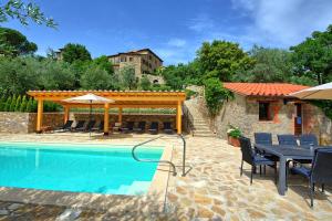 Un patio con mesa y sillas junto a una piscina. en Villa Collina by PosarelliVillas, en Montegiove