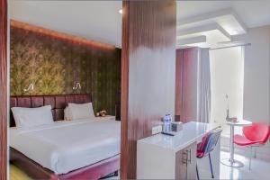 a bedroom with a bed and a desk with a red chair at Empress Hotel Makassar City Center by LIFE in Makassar