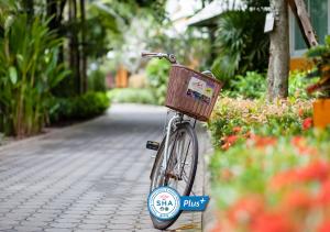 a bike with a basket parked on a sidewalk at Baan Amphawa Resort & Spa - SHA Certified in Amphawa