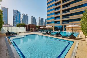 a large swimming pool with chairs and a building at Radisson Blu Residence, Dubai Marina in Dubai