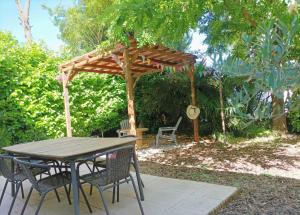 a wooden table and chairs under a wooden umbrella at La douce-Maison-jardin in Montauban
