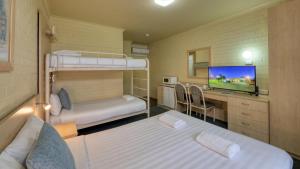 a small room with two bunk beds and a desk at Junee Motor Inn in Junee
