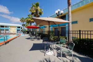 eine Terrasse mit Tischen, Stühlen und einem Sonnenschirm in der Unterkunft Garnet Inn & Suites, Orlando in Orlando