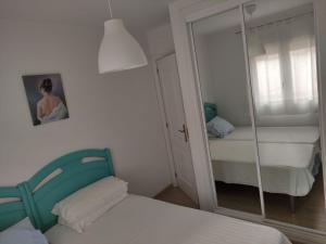 1 dormitorio con espejo, 1 cama y 1 silla en Carvajal - Balcon de Benalmadena, en Benalmádena