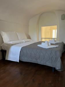 una camera da letto con un letto grande con lenzuola e cuscini bianchi di Palazzo Porta a Procida