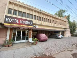 un hotel merkin con un coche aparcado delante de él en Hotel Mehran Multan en Multán