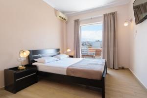 een slaapkamer met een bed en een groot raam bij Archontiki City Hotel in Chania