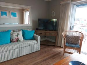 a living room with a couch and a flat screen tv at Belle View @ Knysna Quays in Knysna