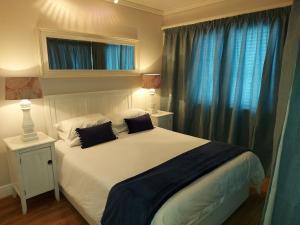 a bedroom with a large white bed with blue curtains at Belle View @ Knysna Quays in Knysna