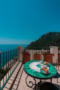 a table on a balcony with a view of the ocean at Maison Ciccio - il Monticello con Sauna Privata in Positano