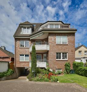 ein großes Backsteinhaus mit Balkon oben in der Unterkunft Ferienwohnung mit Meerblick Grimmershörnbucht in Cuxhaven