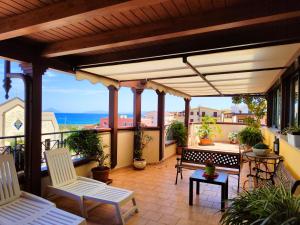 un patio con 2 sillas blancas en el balcón en "Appartamento del Mare Gliaca" con vista Isole Eolie,ampia terrazza,wifi e parcheggio gratuito, en Piraino